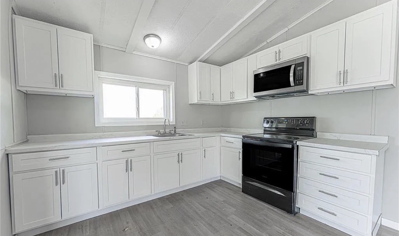 Renovated white kitchen from dining area angle with pendant lighting
