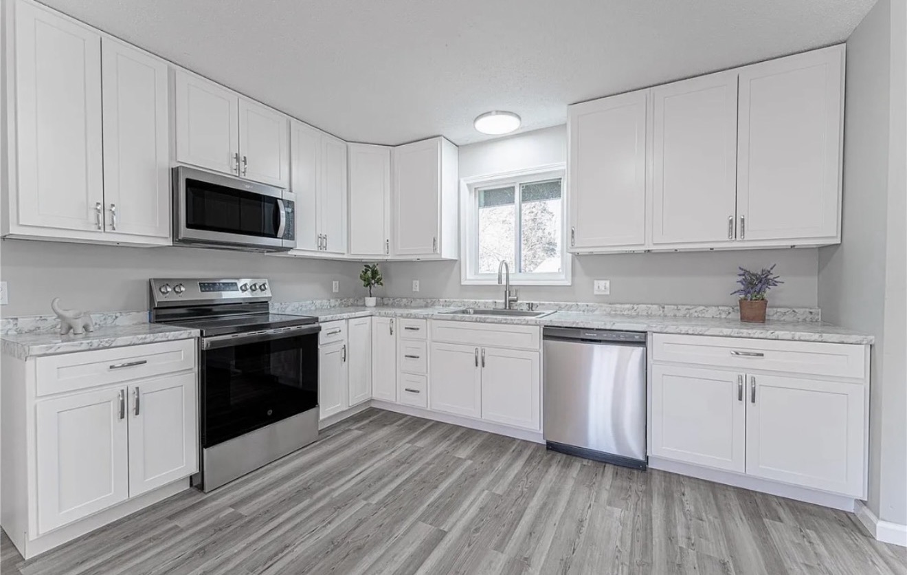 Bright white kitchen remodel with stainless appliances and grey flooring in Wentzville