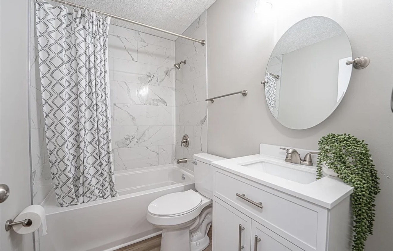 White bathroom vanity and freestanding tub with marble tile surround