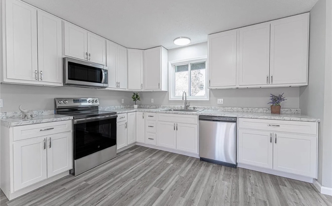 Wide angle of newly remodeled white kitchen with stainless appliances