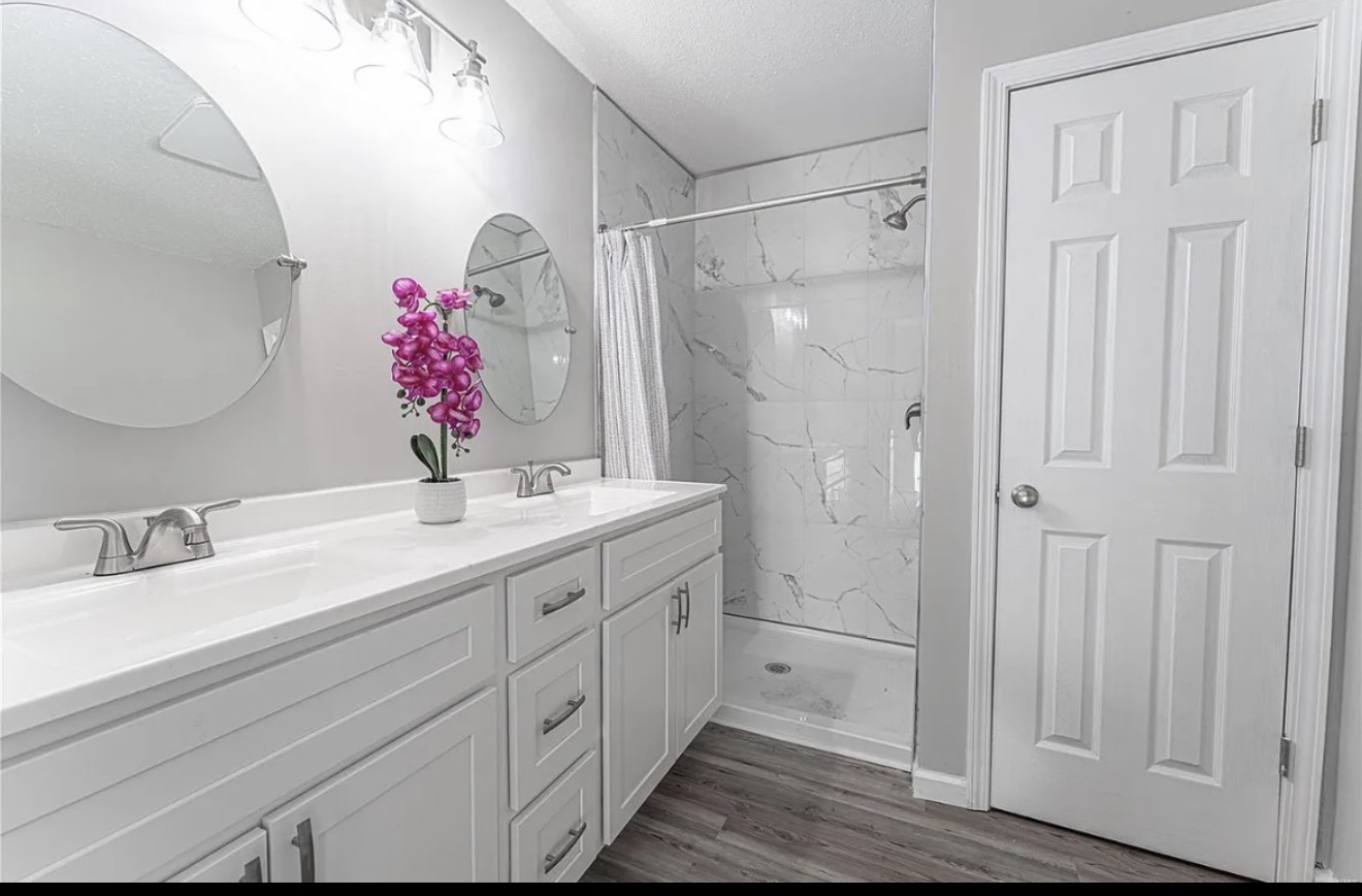 Modern white double vanity bathroom remodel with marble tile shower