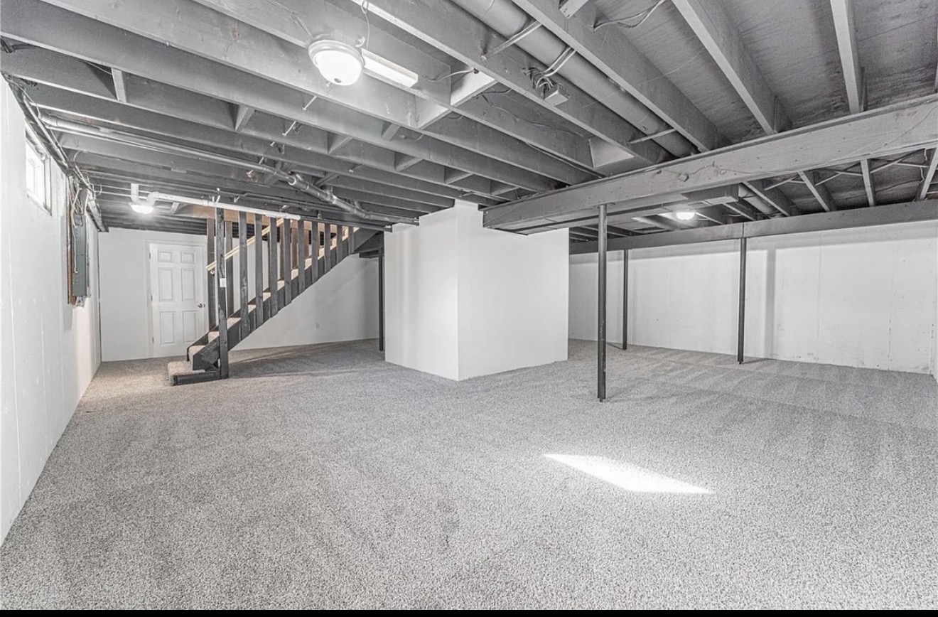 Large unfinished basement remodel in progress with new grey carpet